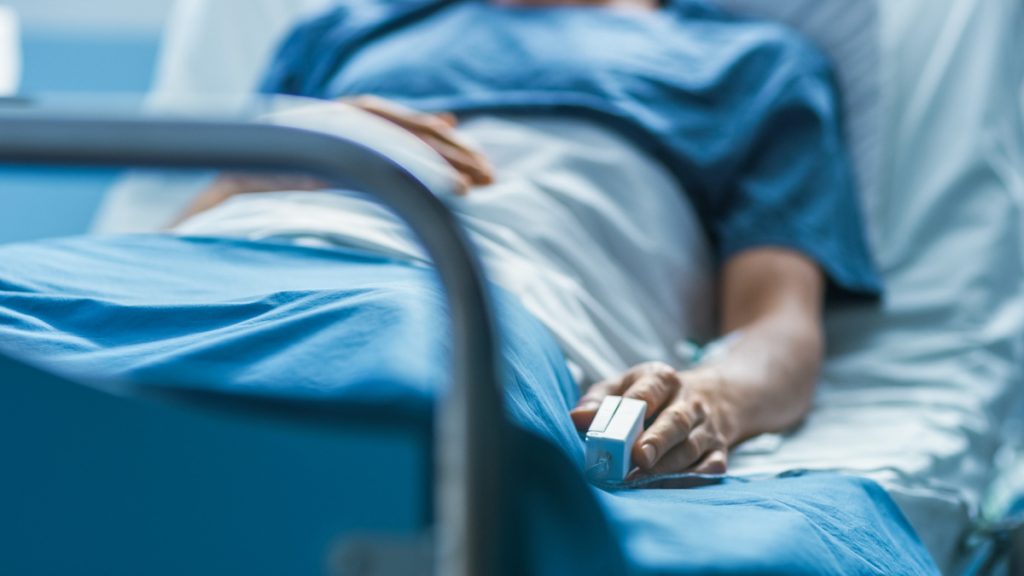 En el hospital, un paciente enfermo duerme en la cama. El Monitor de Frecuencia Cardíaca está en su dedo.
