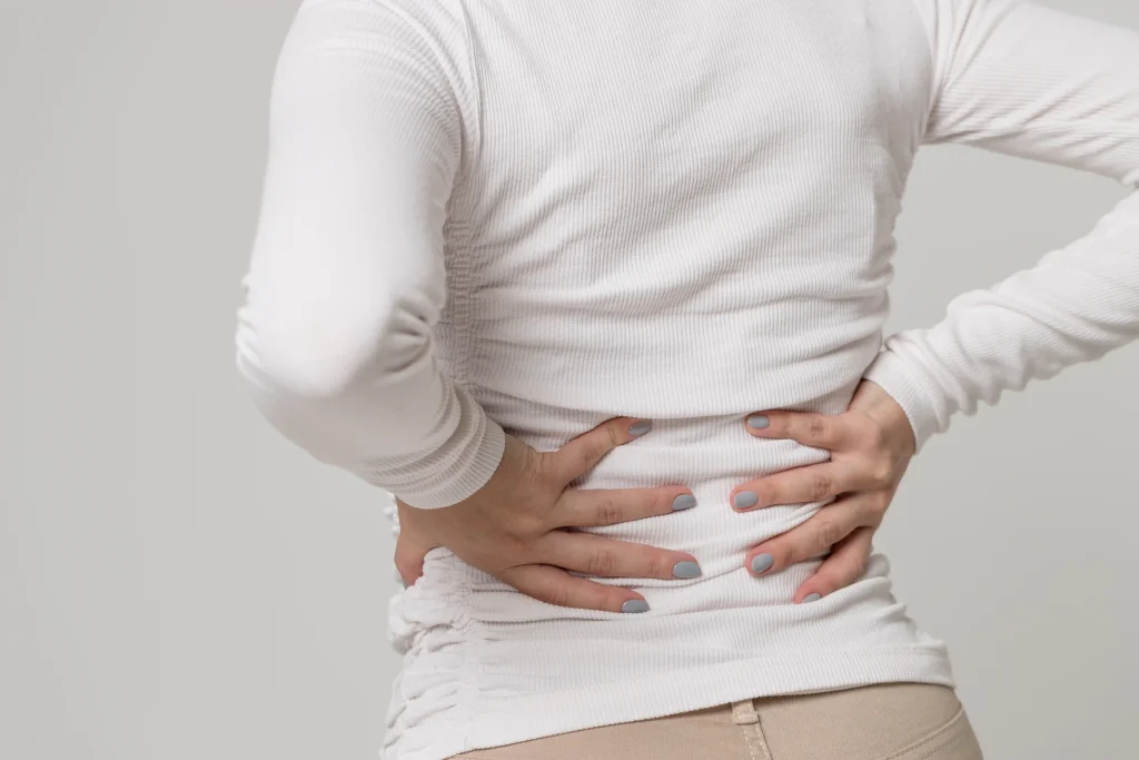 Close-up of a woman experiencing back pain, highlighting discomfort from muscle strain or spinal issues related to musculoskeletal disorders.